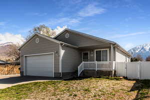 Single story home with a mountain view, driveway, a porch, fence, and a garage