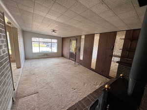 Spare room featuring carpet floors, a wood stove, and wood walls