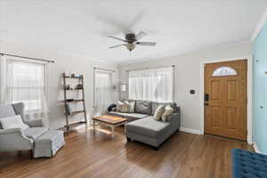 Living area featuring hardwood flooring, crown molding, ceiling fan, and a wealth of natural light