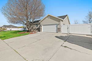 View of side of home featuring a garage, fence, a gate, and a lawn