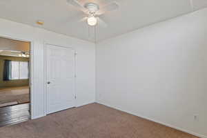 Unfurnished bedroom with ceiling fan and carpet flooring