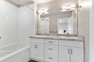 Bathroom with bathing tub / shower combination, double vanity, and a sink