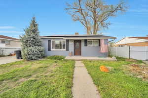 View of front of home featuring brick siding, a front lawn, fence, and solar panels