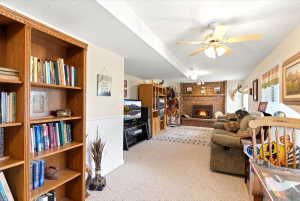 Spacious entertainment area featuring a brick fireplace, built-in wooden shelving, and recessed lighting