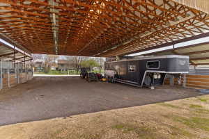 Spacious covered equestrian facility featuring multiple stalls with wood and metal construction
