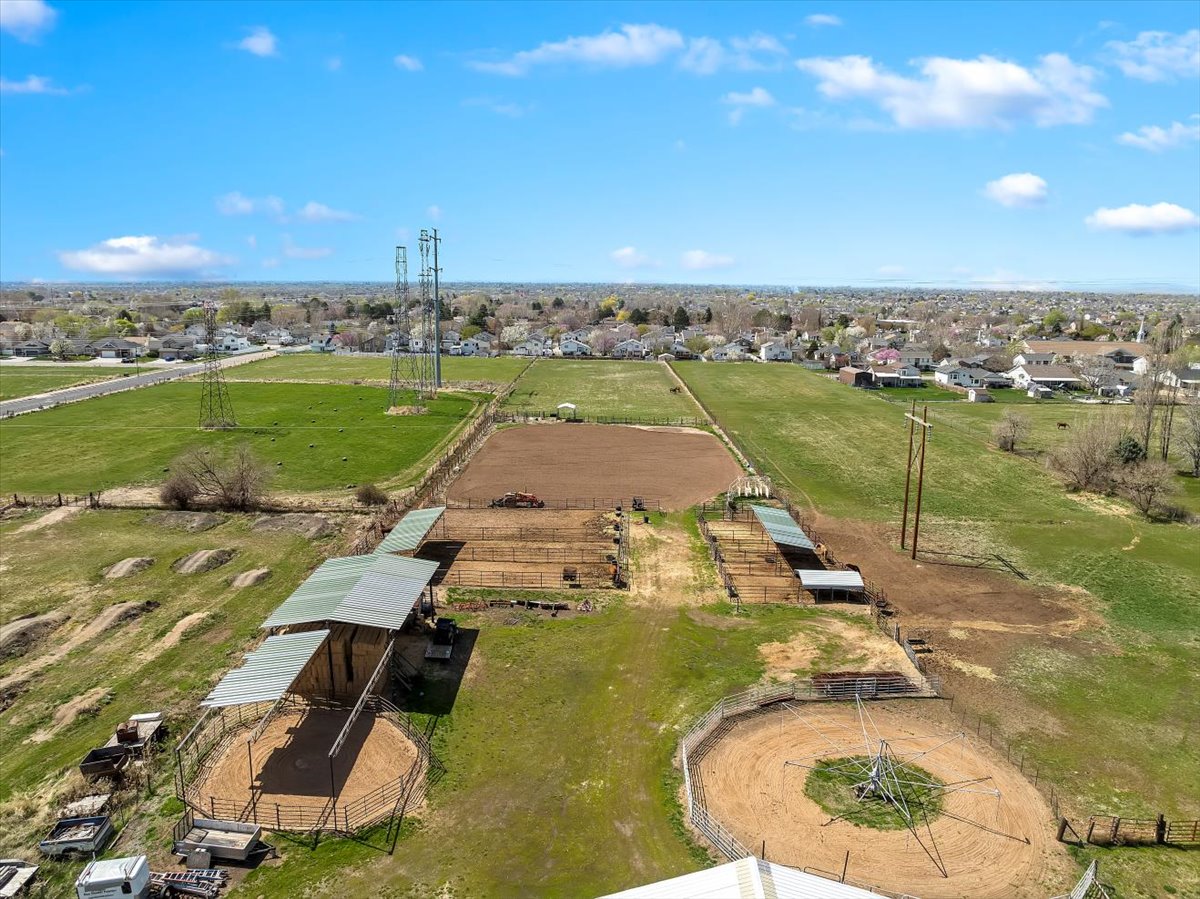 Expansive equestrian property featuring multiple fenced paddocks, covered stalls, and circular training pens
