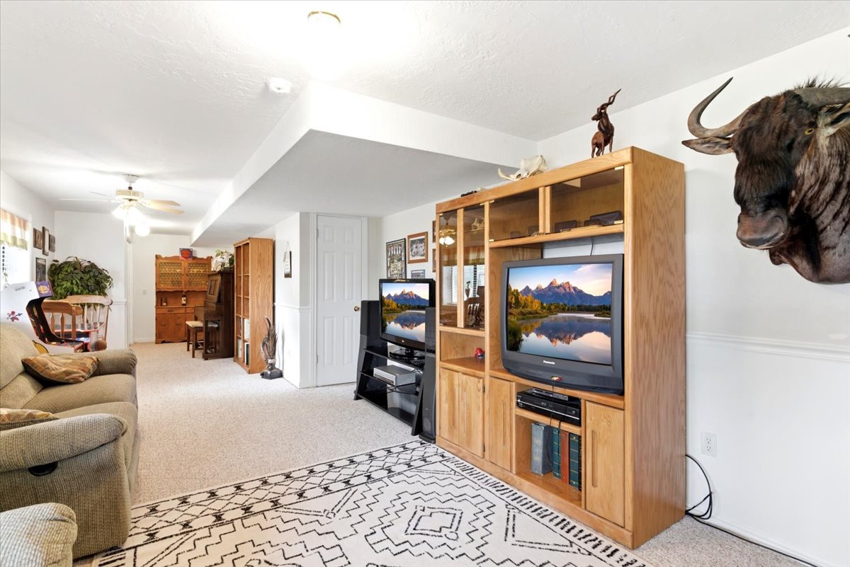 Spacious room featuring neutral carpeting, recessed lighting, and a built-in entertainment center with wood-finish cabinetry