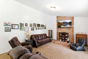Living area featuring a brick and wood-paneled accent wall, a brick hearth, and wall-to-wall carpeting
