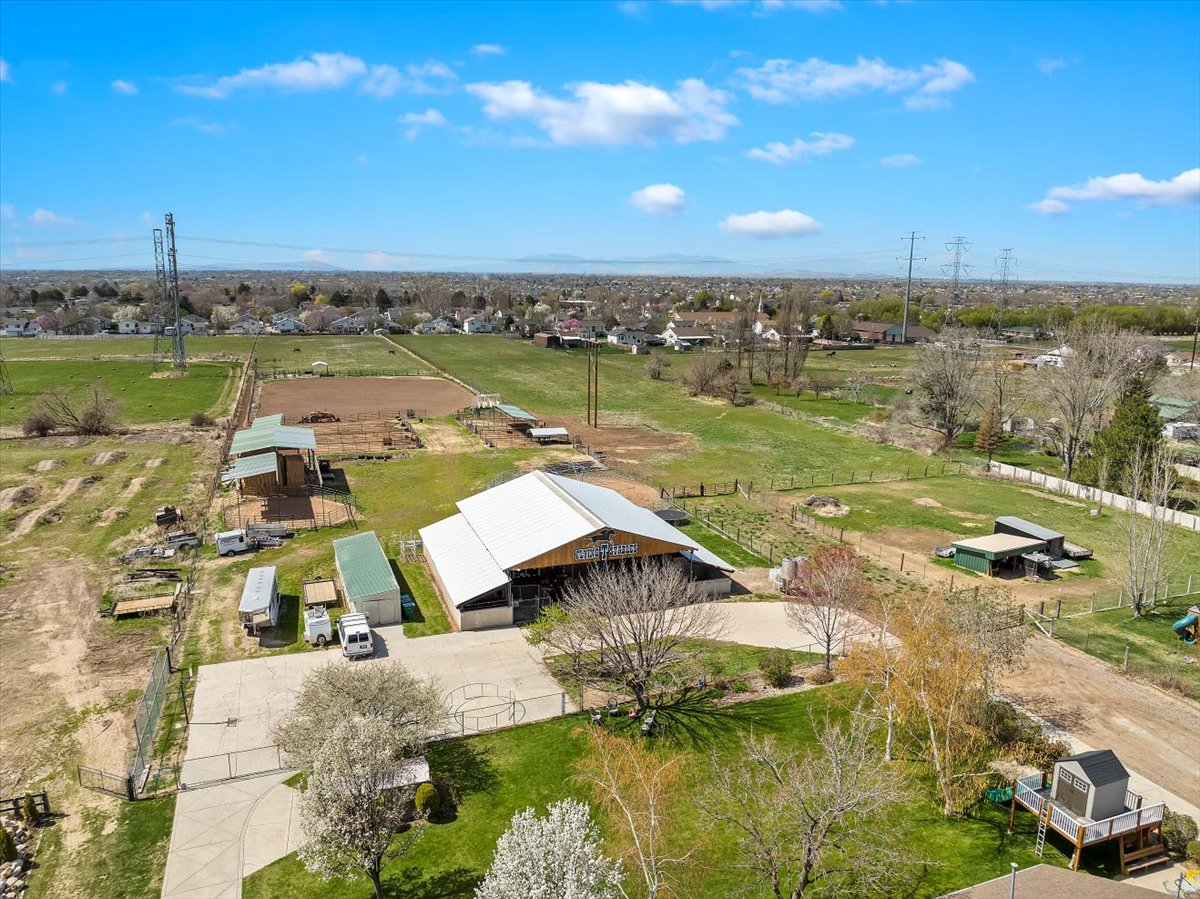 Expansive property featuring a large barn structure with a light-colored roof, multiple outbuildings, and fenced paddocks