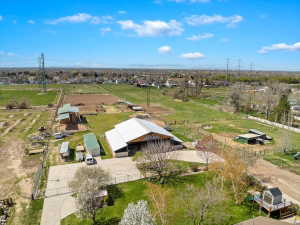 Expansive property featuring a large barn structure with a light-colored roof, multiple outbuildings, and fenced paddocks