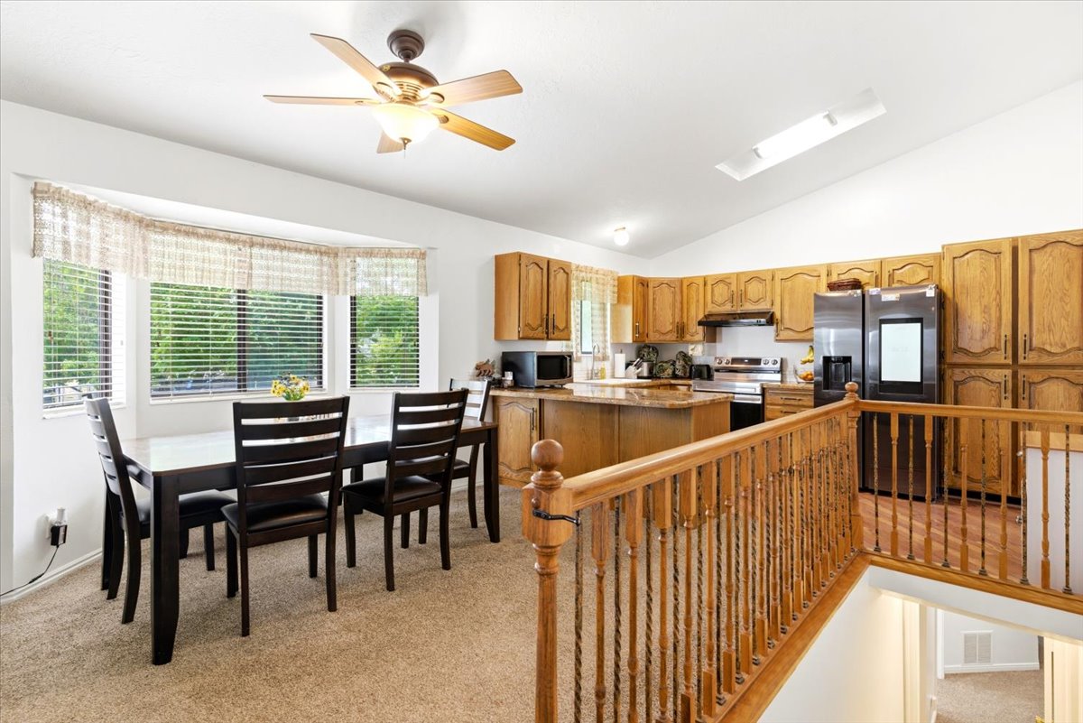 Open-concept kitchen and dining area featuring warm wood cabinetry, a central island with countertop seating, and a bay window