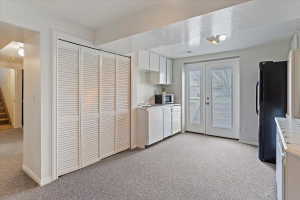 Carpeted room featuring louvered bi-fold closet doors, white cabinetry, a single-basin sink, and double glass-paneled patio doors