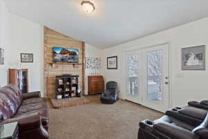 Spacious living area featuring a vaulted ceiling and a brick-accented wall with a fireplace hearth