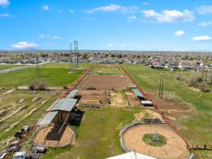 Expansive agricultural parcel featuring multiple fenced enclosures, covered structures, and two round pens