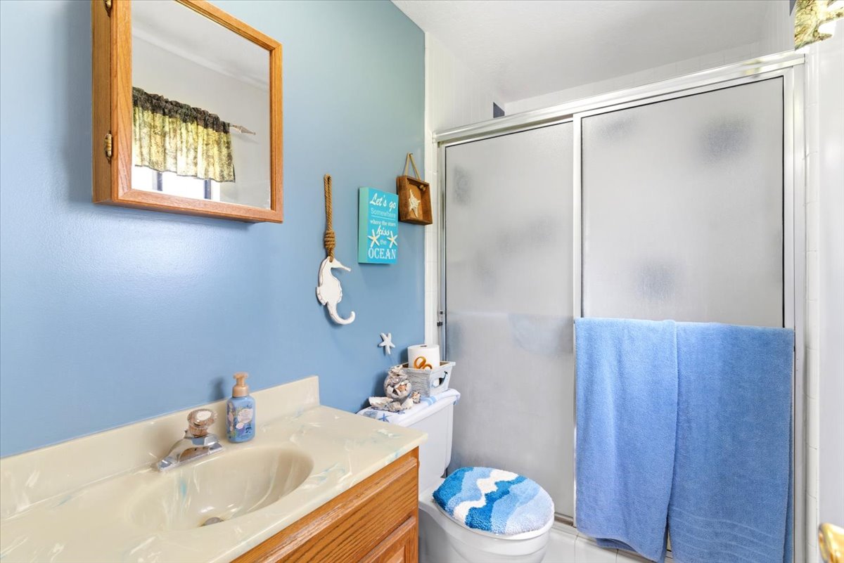 Bathroom featuring a wood-finish vanity with an integrated sink and a cultured marble countertop