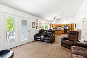 Open-concept living area featuring a vaulted ceiling and light brown carpeting