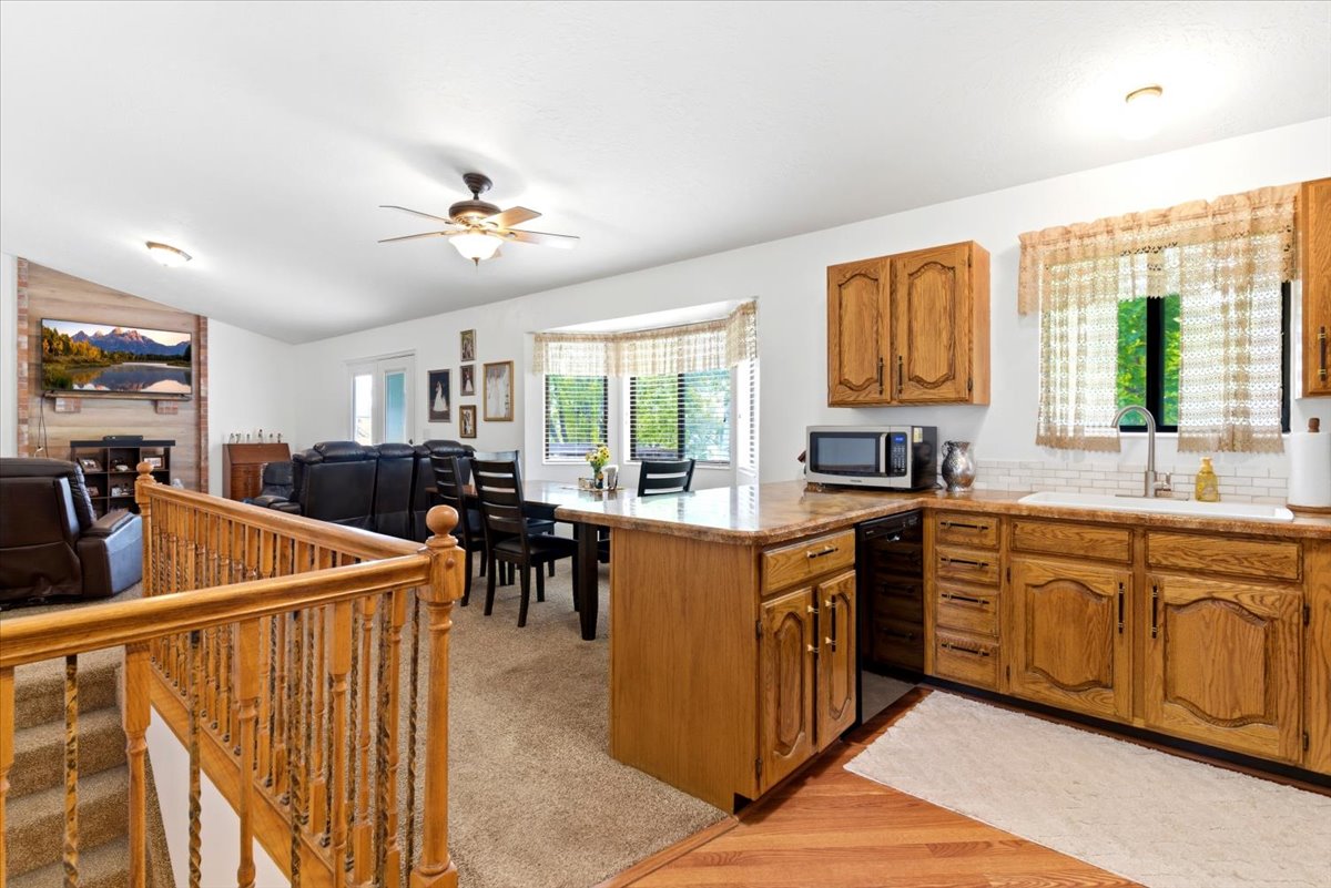 Open-concept kitchen featuring wood cabinetry, solid surface countertops, and a subway tile backsplash