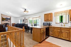 Open-concept kitchen featuring wood cabinetry, solid surface countertops, and a subway tile backsplash