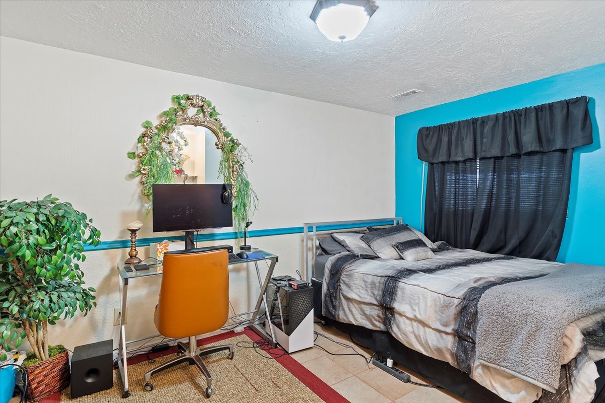 Bedroom featuring a paneled ceiling with flush-mount lighting, two-tone wall design, and tile flooring