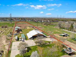 Expansive property featuring a large barn structure with a light-colored roof, a dirt riding arena, and multiple outbuildings