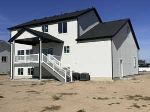 Rear view of property featuring a patio area, stairway, roof with shingles, and stucco siding
