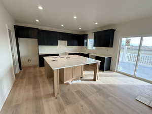 Kitchen featuring a center island, recessed lighting, light wood-style flooring, light stone counters, and a kitchen bar
