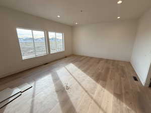Empty room featuring light wood-type flooring and recessed lighting