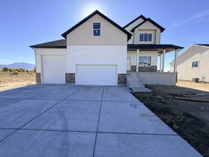 View of front of house featuring stone siding, covered porch, driveway, and a mountain view