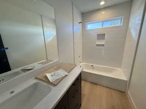 Bathroom with light wood finished floors, vanity, and bathtub / shower combination
