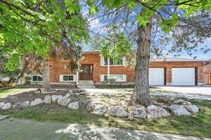 Bi-level home featuring concrete driveway, brick siding, and an attached garage