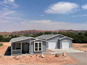 Single story home with driveway, a mountain view, covered porch, board and batten siding, and an attached garage