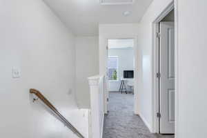 Hall with baseboards, an upstairs landing, and carpet