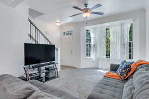 Living area featuring crown molding, ceiling fan, carpet flooring, stairs, and baseboards