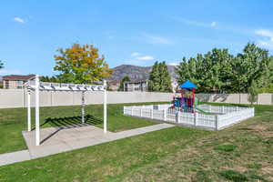 View of community space with a mountain view, a fenced backyard, and playground community