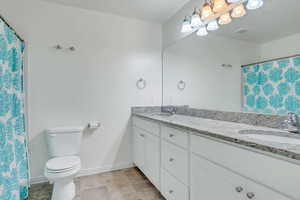 Bathroom with double vanity, baseboards, a sink, and toilet