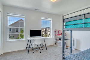 Carpeted bedroom with baseboards, multiple windows, and visible vents