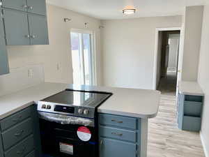 Kitchen with light countertops, a peninsula, stainless steel range with electric cooktop, and light wood finished floors