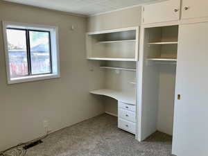 Interior space with visible vents, a closet, built in desk, crown molding, and carpet floors