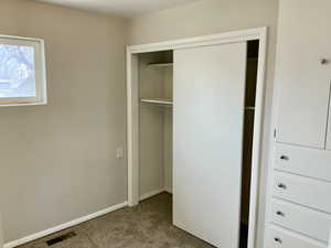 Unfurnished bedroom with a closet, visible vents, baseboards, and carpet