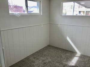 Carpeted empty room with radiator heating unit and a wainscoted wall