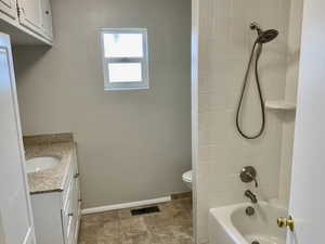 Bathroom featuring visible vents, baseboards, toilet, vanity, and shower / bathtub combination