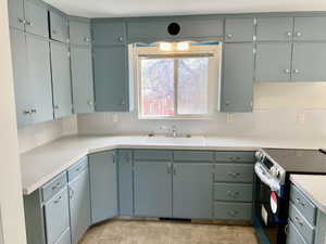 Kitchen featuring electric range, light countertops, and a sink