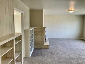Unfurnished living room with wood walls, baseboards, and carpet