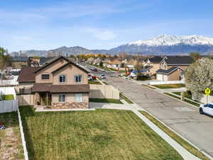 View of front of house featuring a residential view, stucco siding, a mountain view, a front lawn, and fence