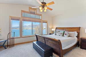 Bedroom featuring baseboards, high vaulted ceiling, a water and mountain view, and light colored carpet