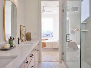 Ensuite bathroom with double vanity, a stall shower, ensuite bath, a ceiling fan, and a sink