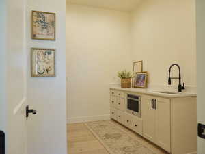 Kitchen featuring baseboards, light countertops, stainless steel oven, light wood finished floors, and a sink