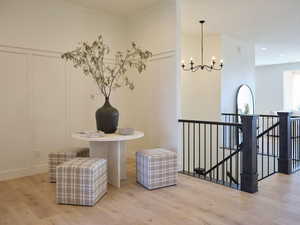 Corridor with an upstairs landing, a chandelier, and wood finished floors