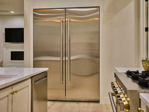 Kitchen with recessed lighting, light wood-style flooring, cream cabinets, light stone countertops, and appliances with stainless steel finishes