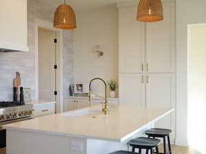 Kitchen with tasteful backsplash, stainless steel range with gas stovetop, a sink, and light stone countertops